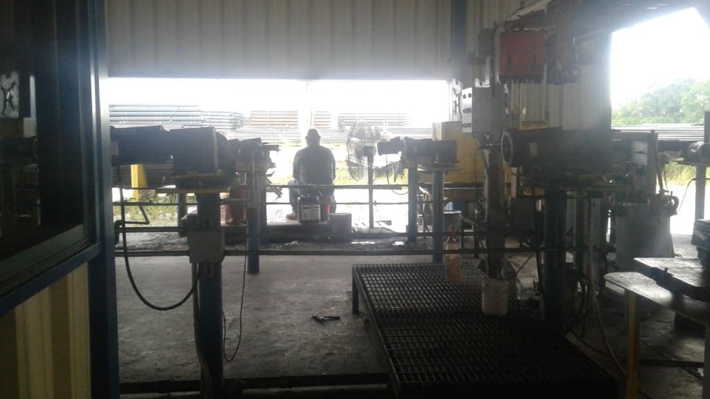 Looking out from the Tubular Services shop bay toward stacks of industrial pipe in the yard