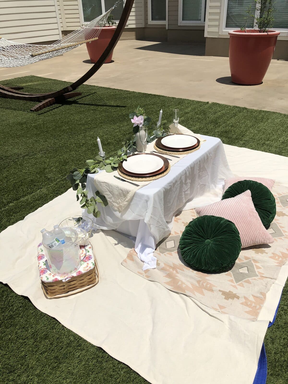 Styled outdoor picnic with emerald pillows, copper chargers, and a picnic basket